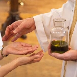 Priest annointing woman's hands with oil